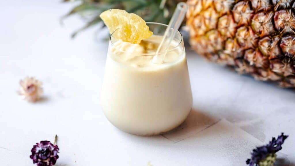 A clear glass filled with a creamy yellow smooth.
