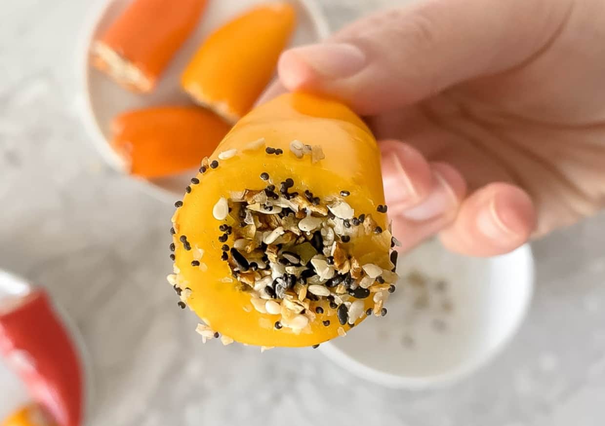 A hand holding a hollowed-out mini pepper filled with seasoning.