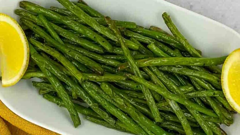 Green beans with lemon wedges in a serving dish.