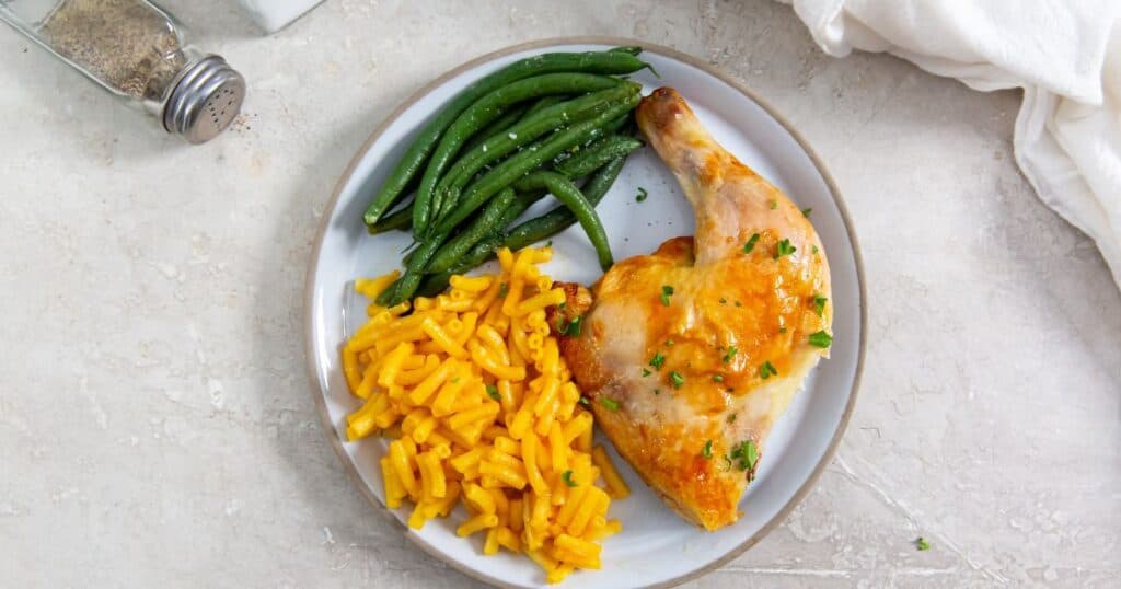 Trader Joe's Buttermilk Brined half chicken on a plate with green beans and Mac and cheese.