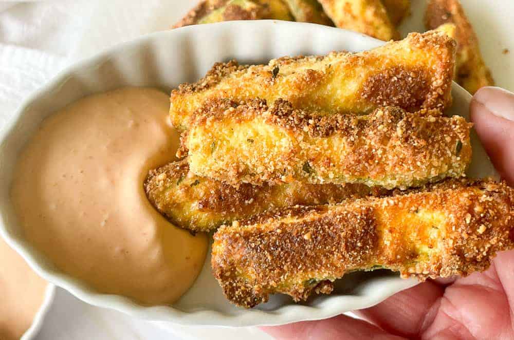 Zucchini fries in a dish with spicy dipping sauce.