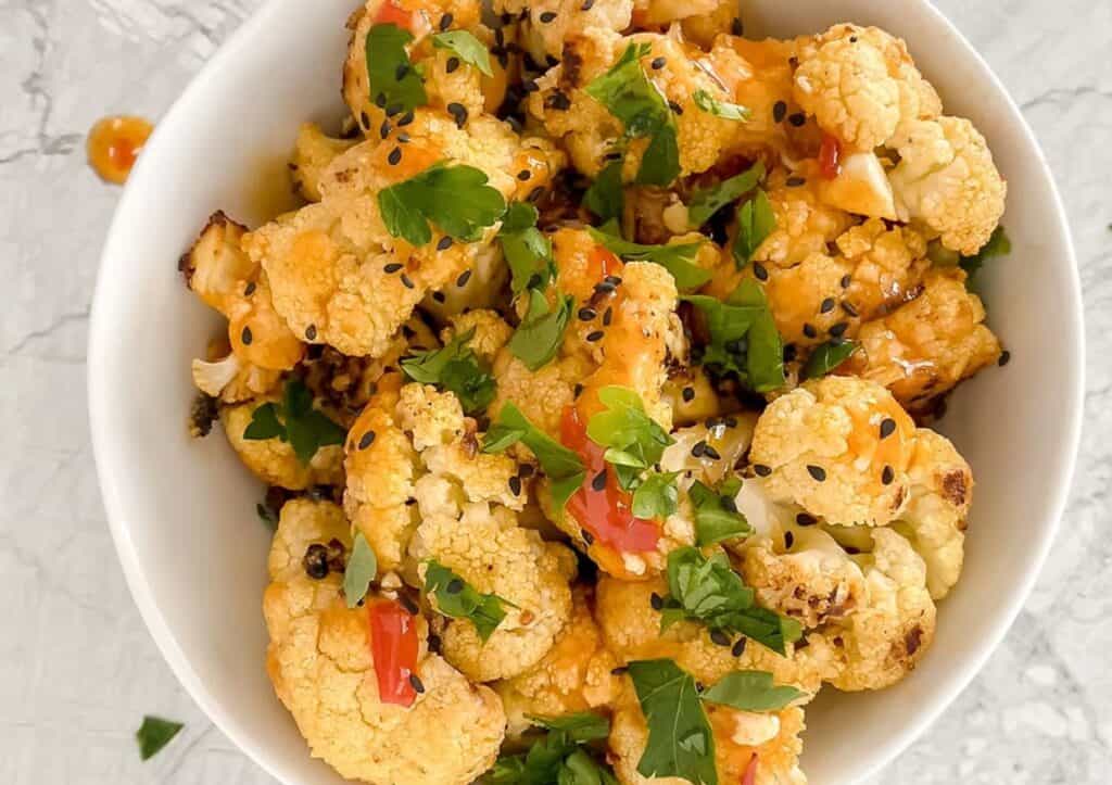 Bang bang cauliflower garnished with fresh parsley in a bowl.