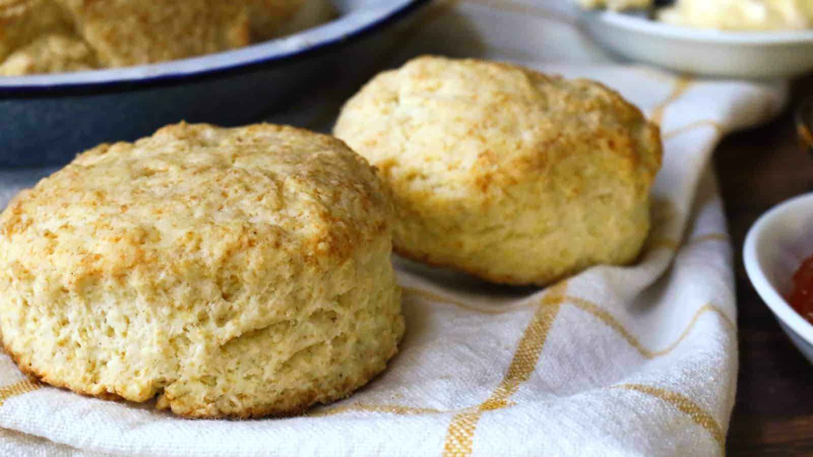 Two baked biscuits on a white and gold towel.