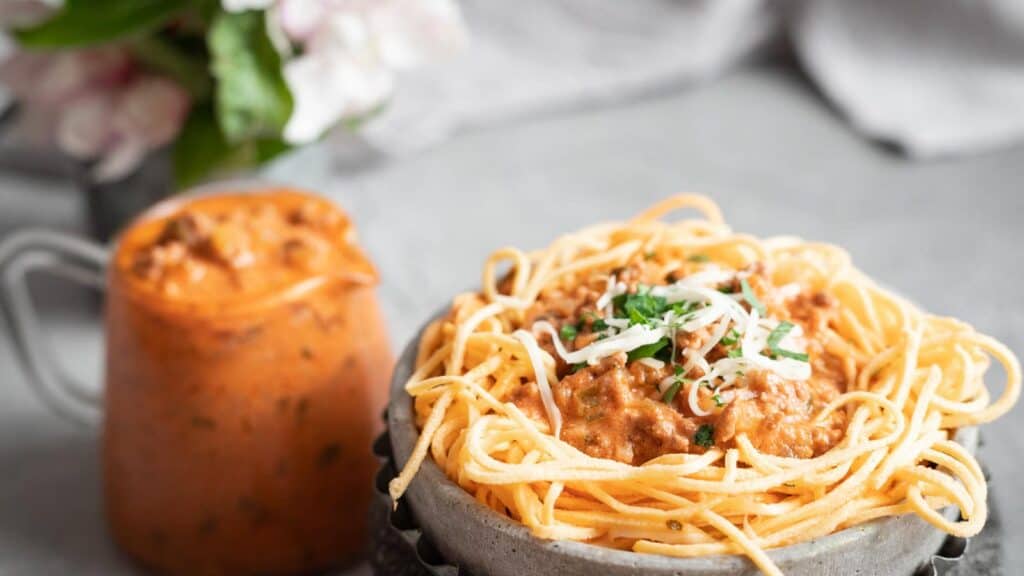 Low Carb Spaghetti Bolognese in a grey bowl with extra sauce on the side.