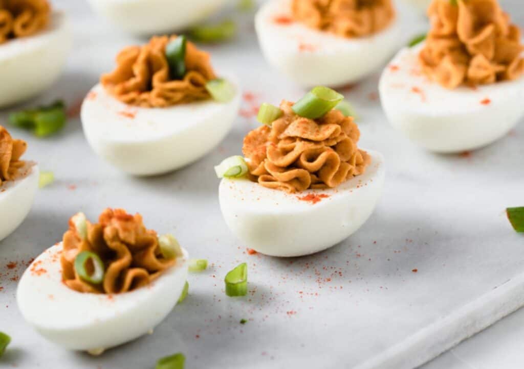 Buffalo deviled eggs garnished with paprika and green onions.
