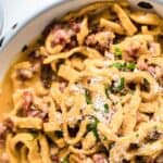 Pasta Carbonara inside a bowl with herbs and bacon.