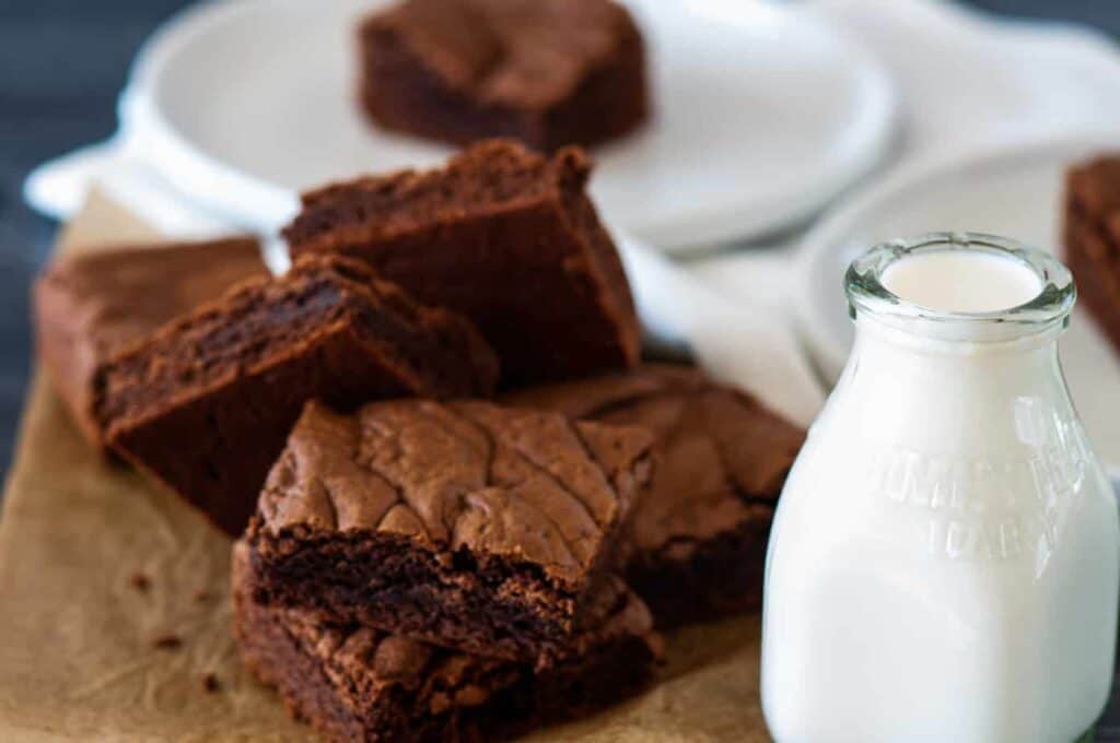 Stack of chocolate cake mix brownies with a jug of milk beside it.