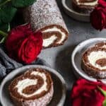 Low Carb Chocolate Roulade on a dark plates with roses around.