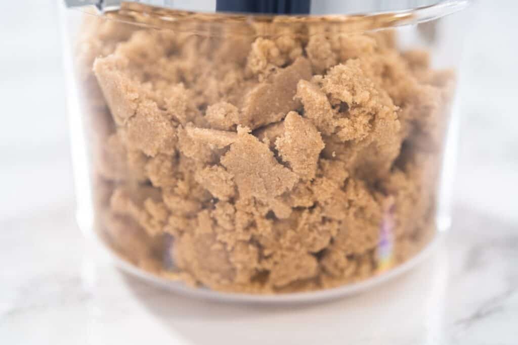 Image shows chunks of brown sugar in a clear glass container.