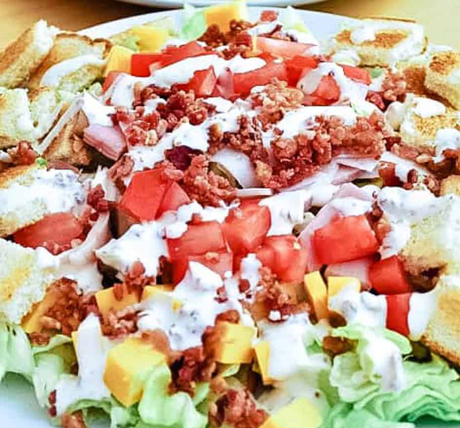 Club Sandwich Salad with tomatoes, cheese, bacon, and dressing.
