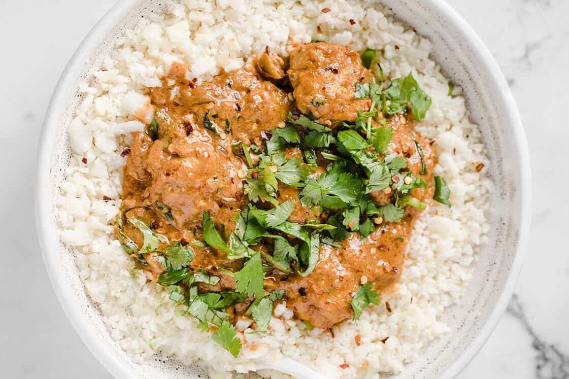 Coconut curry Thai turkey meatballs on top of cauliflower rice in a bowl.