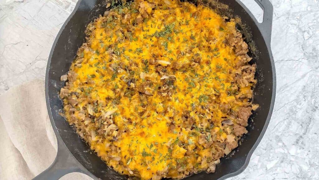 Creamy ground beef and cauliflower rice skillet on a marble countertop.