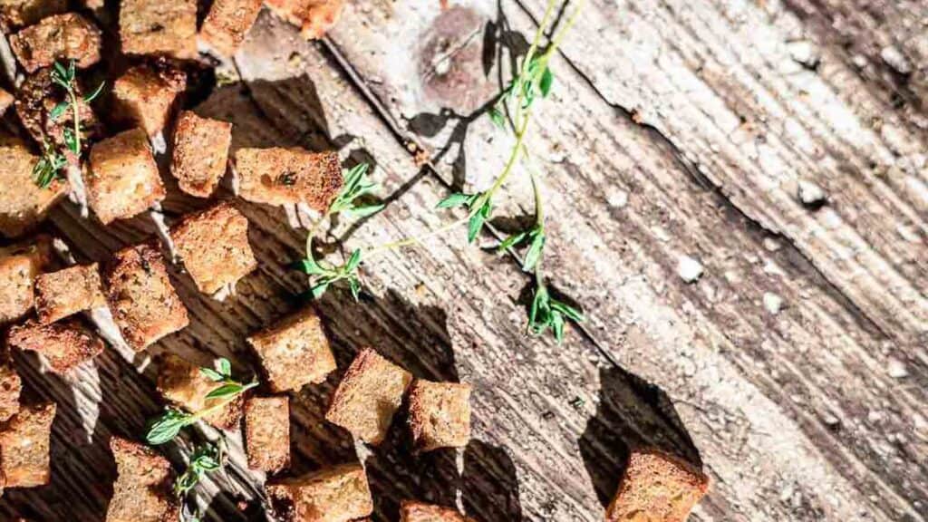Croutons spread on a wood with herbs. 