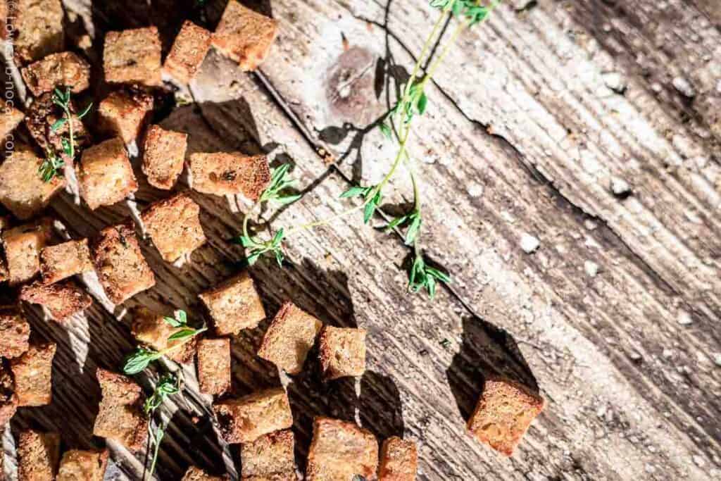 Croutons spread on a wood with herbs.