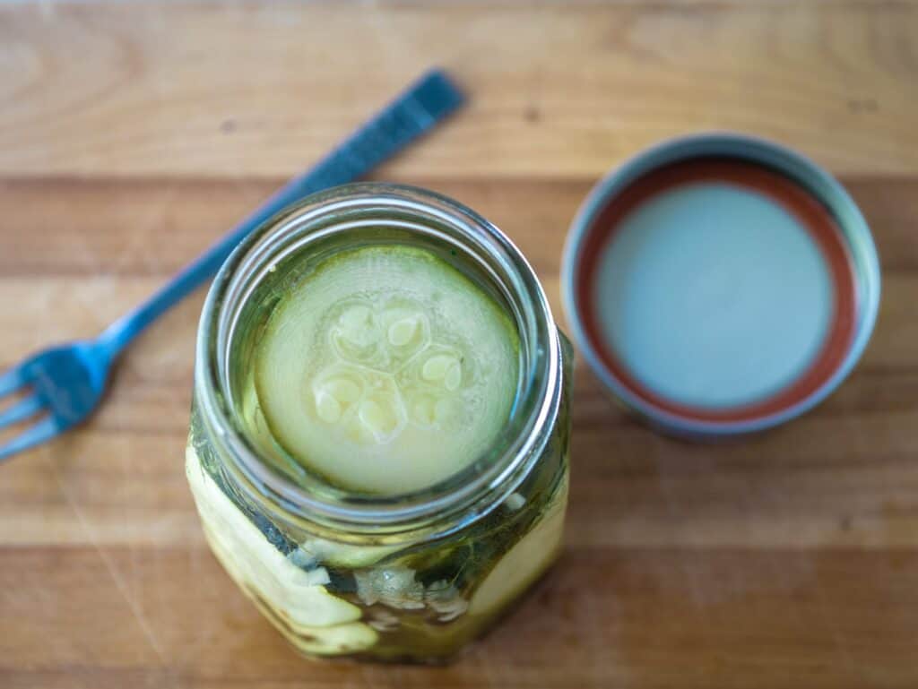 Mason jar of zucchini pickles with the top off to show the zucchini.