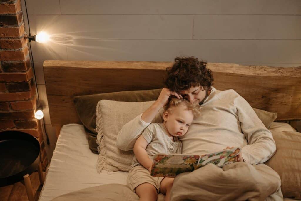 Dad reading bedtime stories to toddler in bed