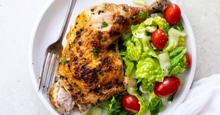 Easy Broiled Chicken Leg Quarters on white plate with fresh salad