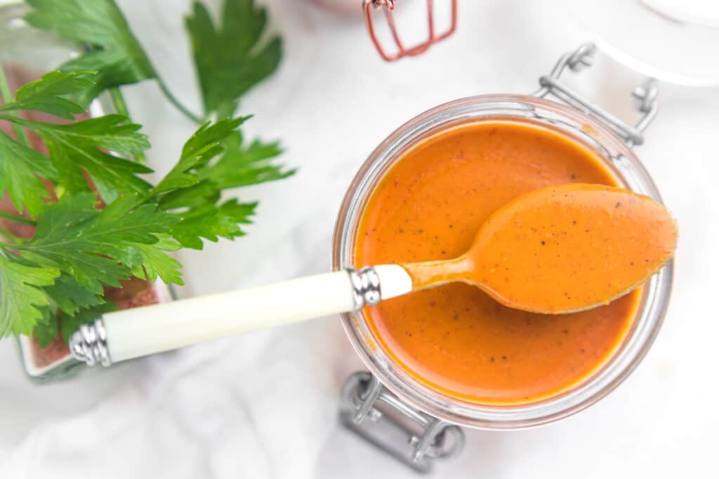 Enchilada sauce in a jug with white spoon. 