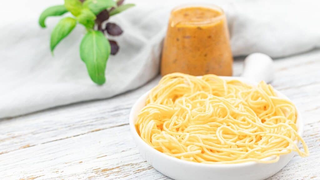 Keto Spaghetti inside a white plate with sauce on the side.