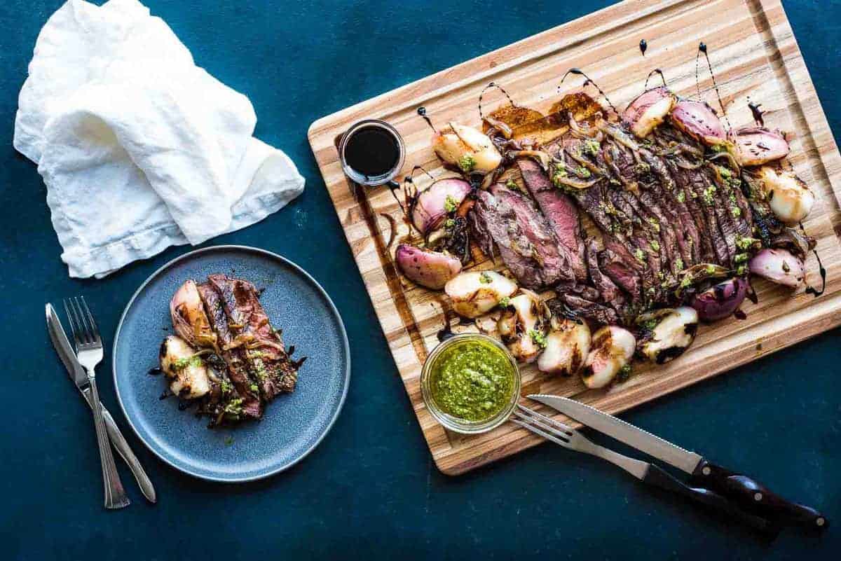 Grilled steak with peaches and onions on a wooden cutting board.