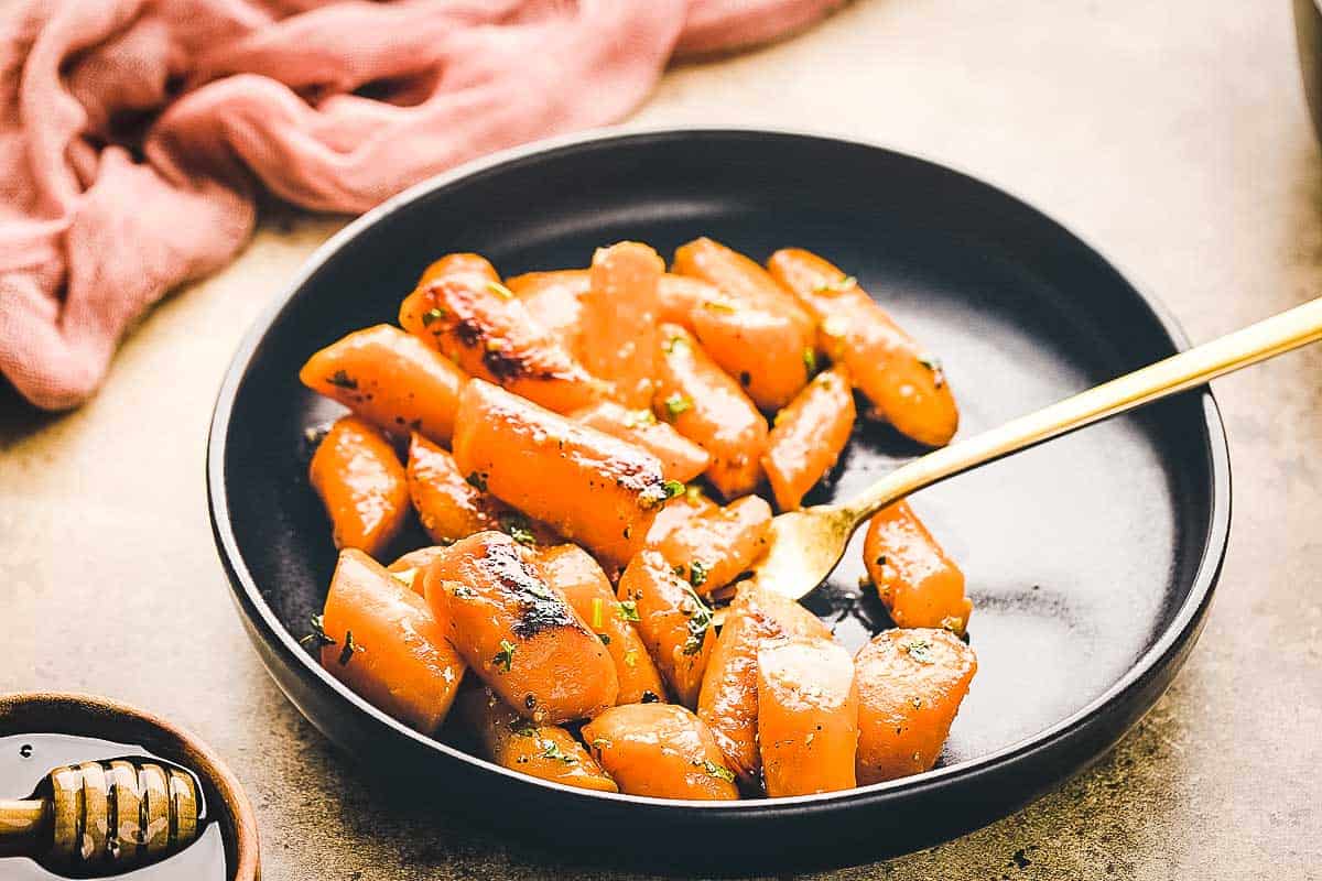 Honey garlic carrots in a black dish.