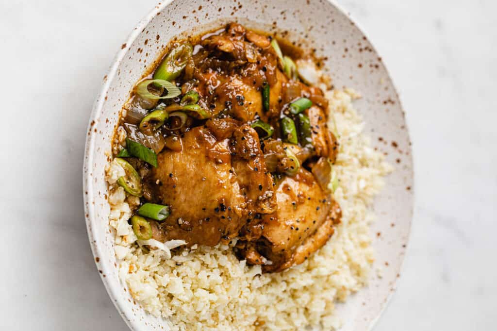A bowl of Instant Pot chicken adobo and cauliflower rice.