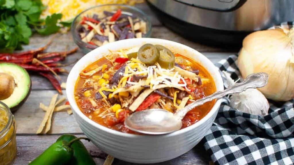 Chicken tortilla soup in a white bowl with a spoon.