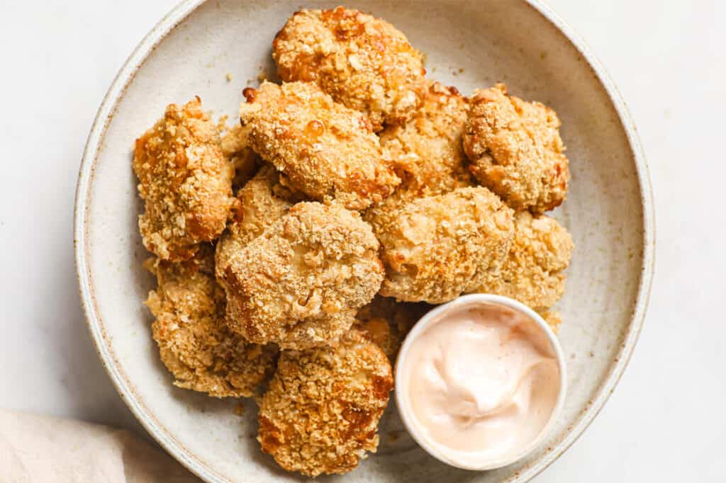 Keto chicken nuggets on a plate with a cup of dipping sauce.