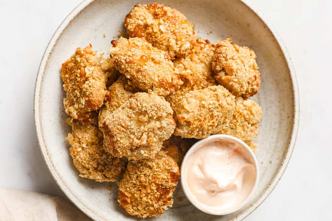 Keto chicken nuggets on a plate with a cup of dipping sauce.