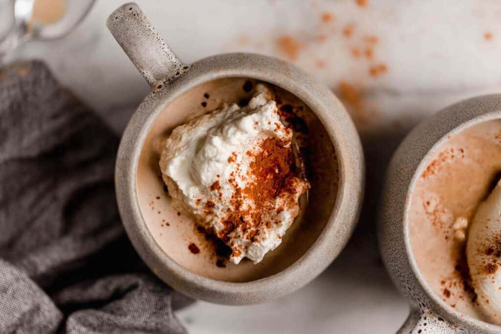 Keto cinnamon dolce latte in a mug topped with whipped cream and cinnamon.