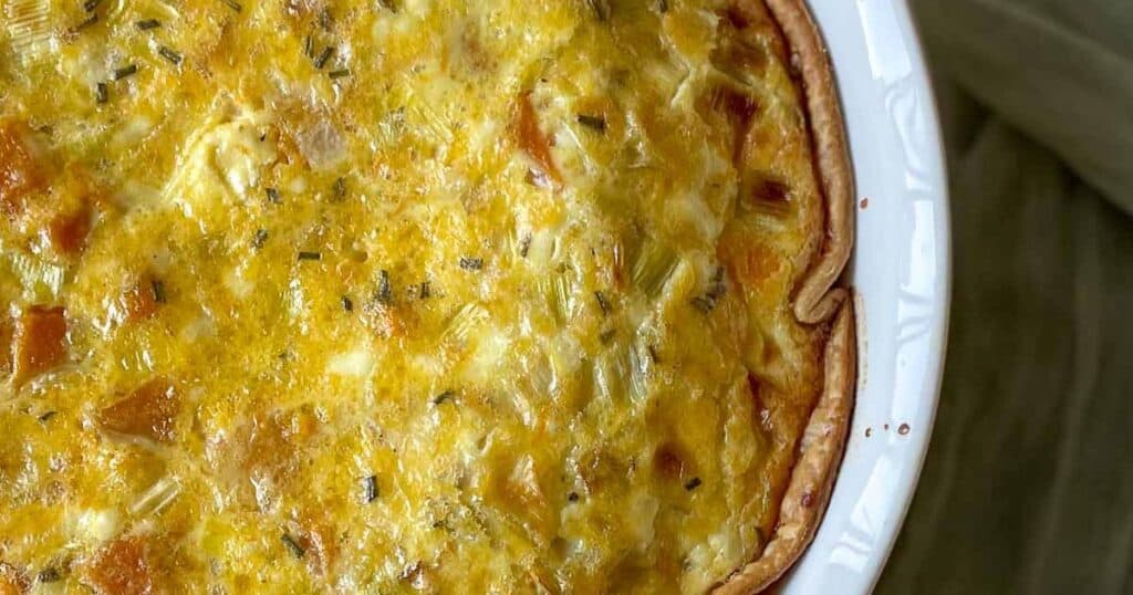 Closeup of leek and squash quiche with a green linen.