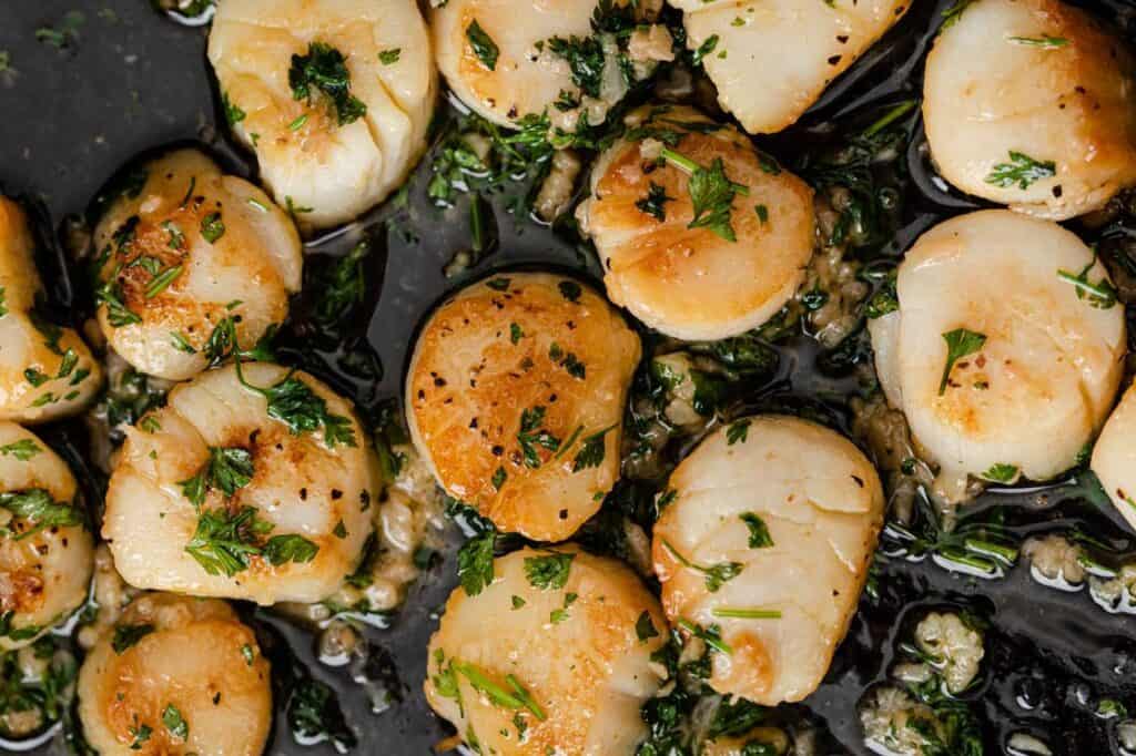 Lemon garlic scallops garnished with parsley in a skillet.