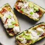 Three loaded zucchini boats on a plate.