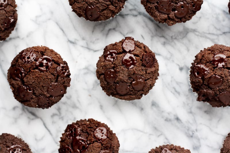 Low-carb triple chocolate zucchini muffins on a marble board.