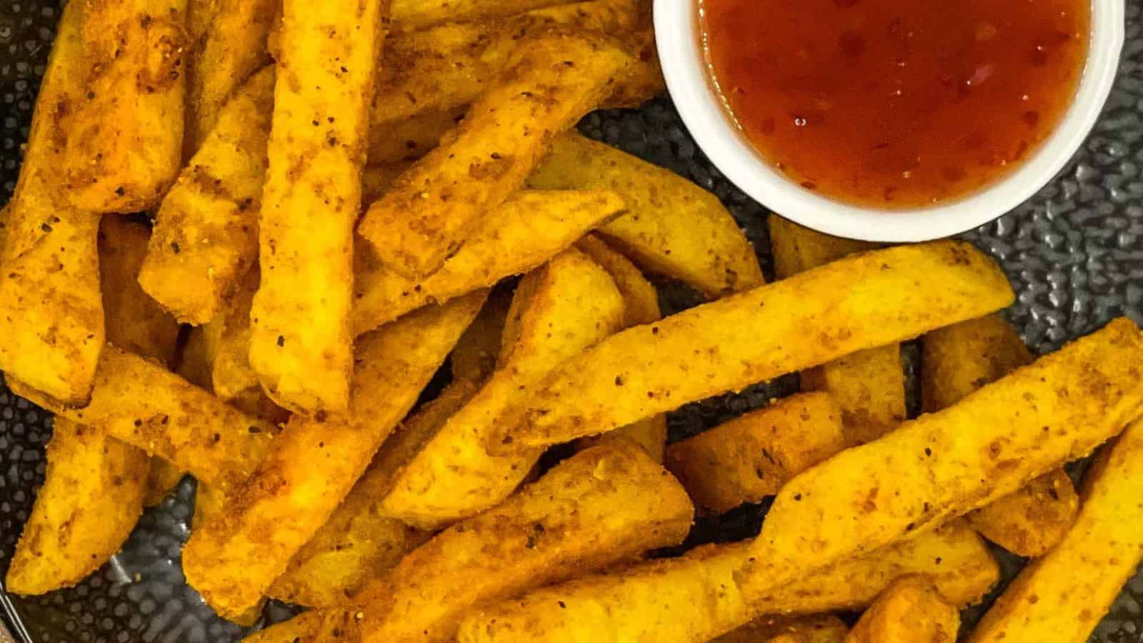 Masala fries on a plate with sweet chili sauce.