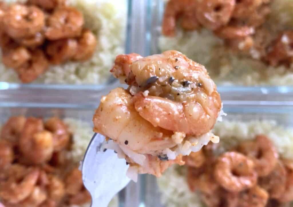 Meal prep cajun shrimp and cauliflower rice on a fork.