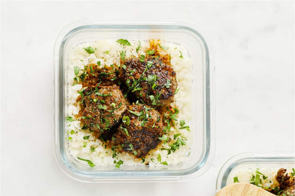 Meal prep low-carb meatballs and cauliflower rice in a glass container.