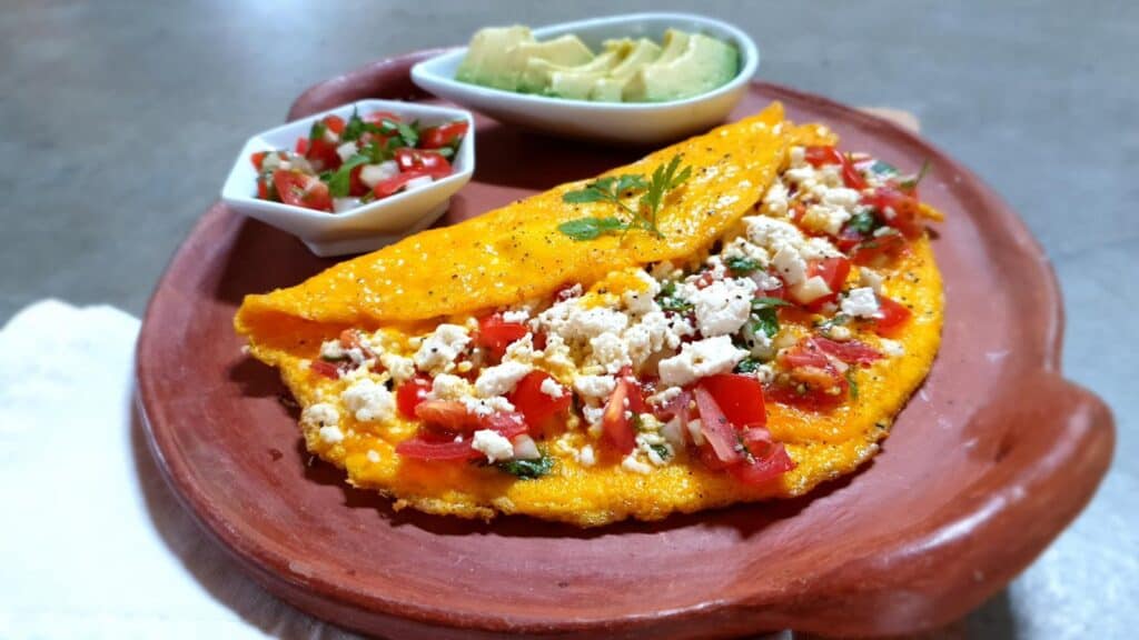 Mexican omelette folded with queso fresco and salsa on earthen serving tray