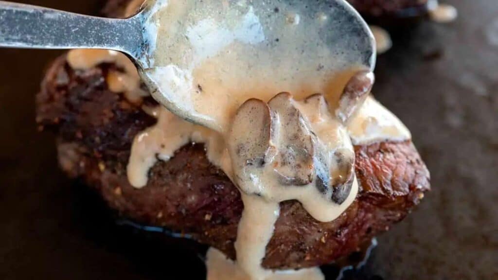 spooning mushroom sauce on filet mignon steaks.