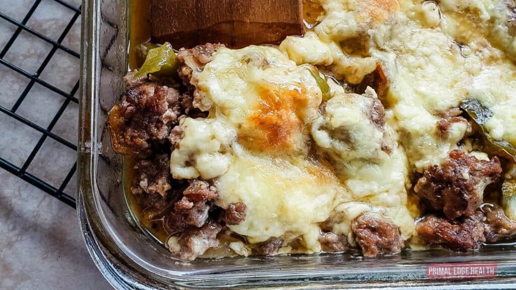 wooden spatula cutting philly cheesesteak casserole from baking dish