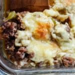 Image shows a wooden spatula cutting philly cheesesteak casserole from baking dish.