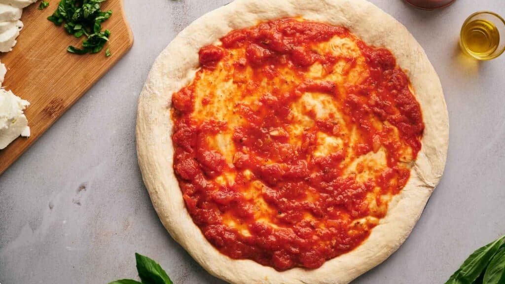 Pizza sauce spread over a pizza crust.