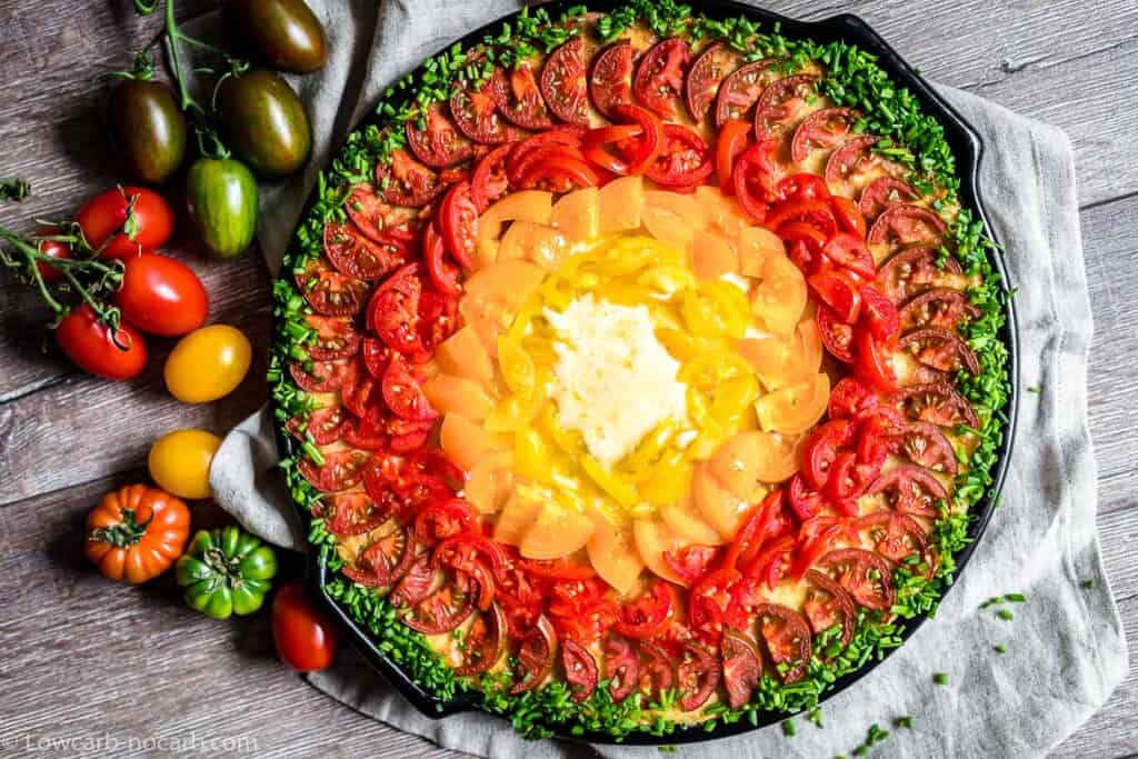 Rainbow Pizza filled with colorful tomatoes and green fresh chives around it. 