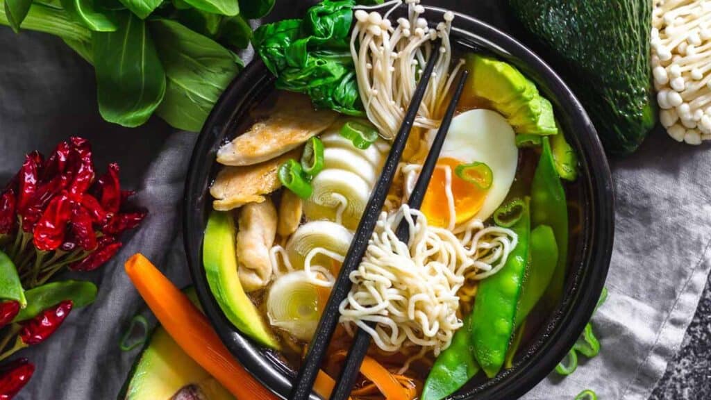 Low Carb Ramen Chicken Noodles in a black bowl with various vegetables and boiled egg.