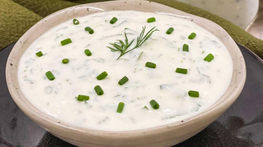 Freshly made ranch dressing in a small dish with chopped chives and dill on the top.