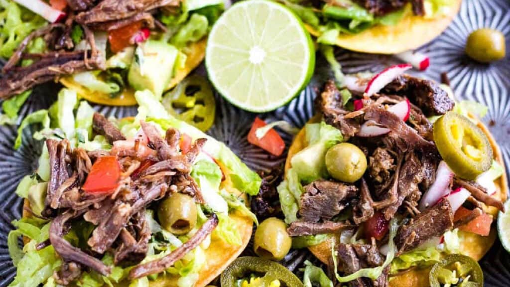 Low angle shot of mini tostadas with salpicon de res or shredded beef salad on top.