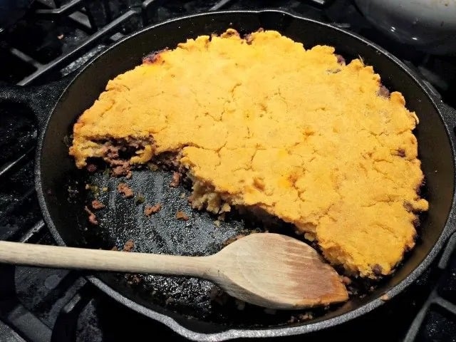 Ground Beef Skillet Tamale in cast iron skillet with wooden spatula
