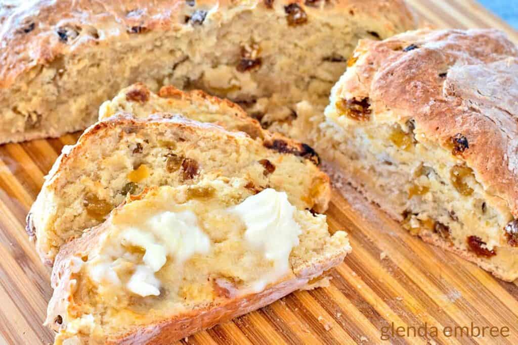 Sliced soda bread with buttered slice in front.