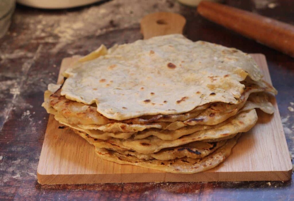 Stack of sourdough starter discard tortillas on a wooden cutting board.