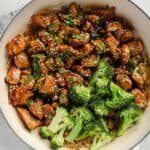 Sticky sauce chicken, broccoli, and sesame seeds in a pot.